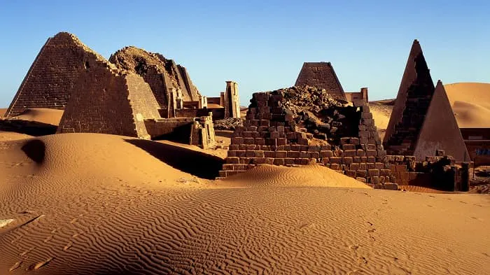 A sand dune with pyramids in the background.