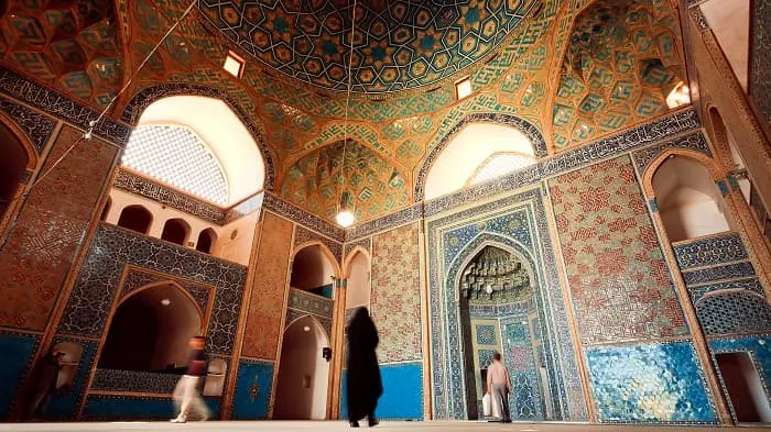 A woman walks through an ornately decorated mosque.
