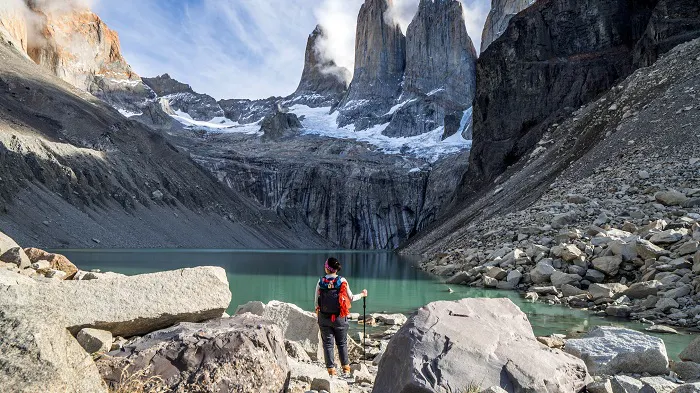 A man standing in front of a lake with mountains in the background.