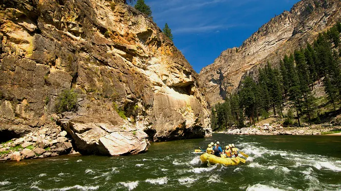 A group of people rafting down a river in a canyon.