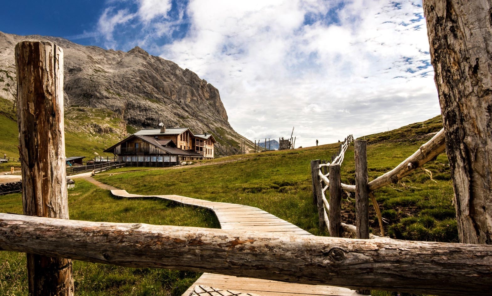 A wooden path leading to a house in the mountains.