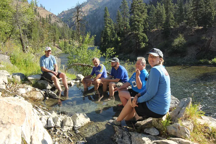 A group of people sitting on rocks near a river.