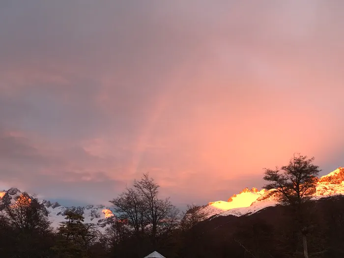 A rainbow in the sky over a snow covered mountain.