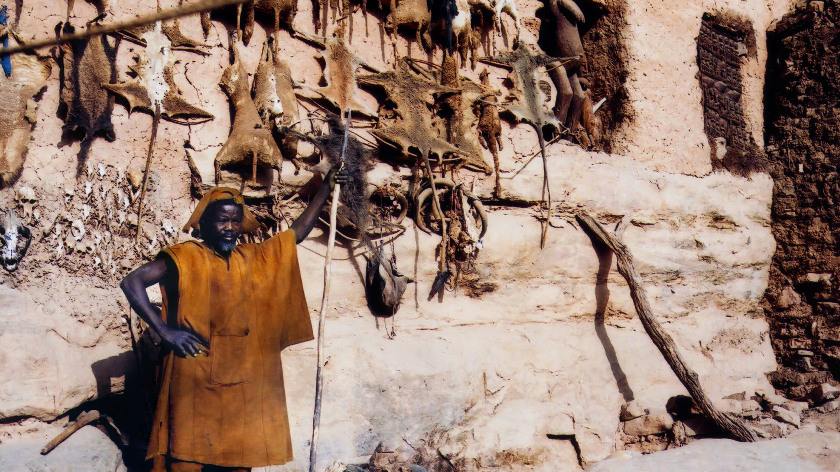 A man standing in front of a building with a lot of dead animals hanging on the wall.