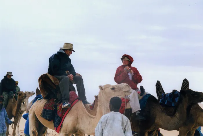 A group of people riding camels in the desert.