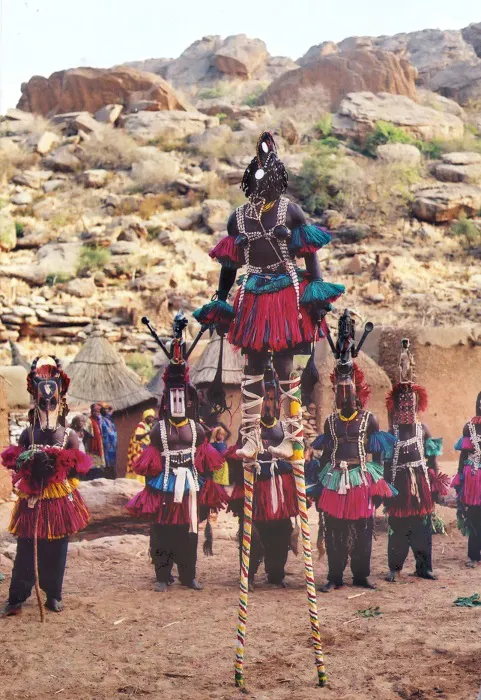 A group of people standing on stilts in a desert.