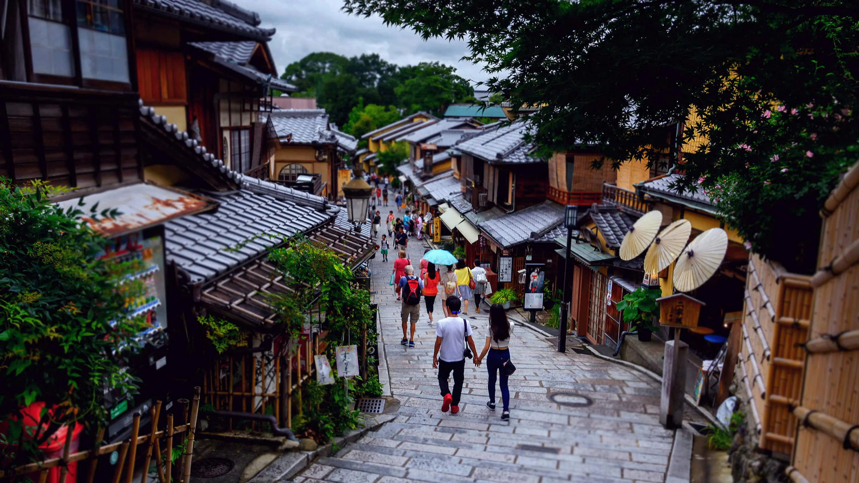 People walking down a narrow street in a japanese village.