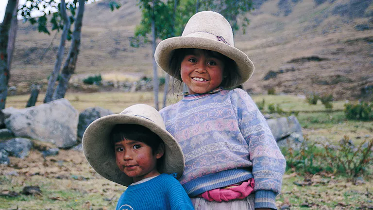 Two children wearing hats in a field.