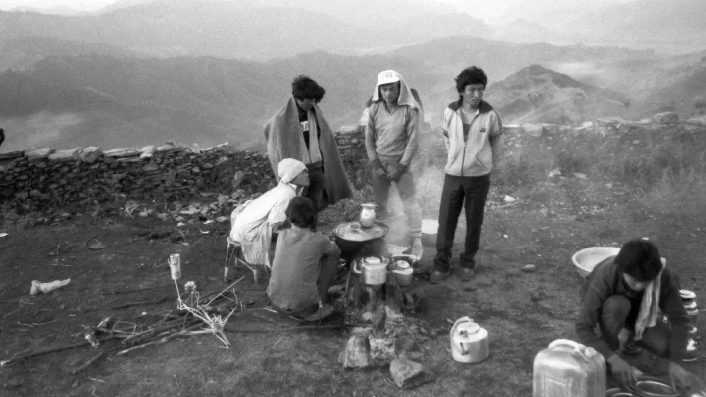 A group of people sitting around a campfire in the mountains.