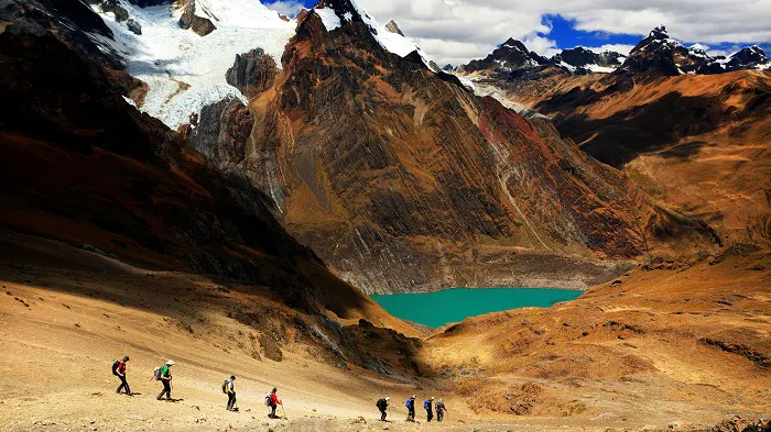 A group of people hiking up a mountain with a lake in the background.