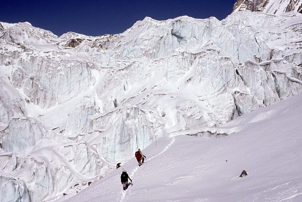 Two people skiing down a snow covered mountain.