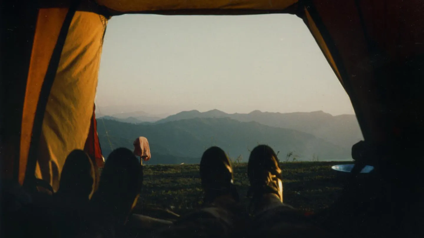 A person's feet in a tent with mountains in the background.