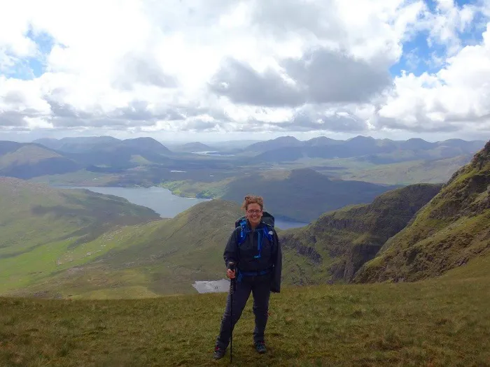 A woman standing on top of a mountain in scotland.