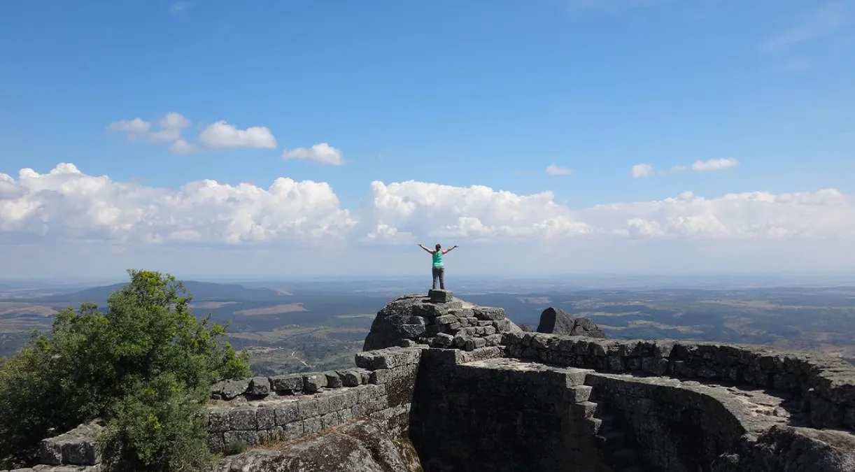 A man standing on top of a rock with his arms outstretched.