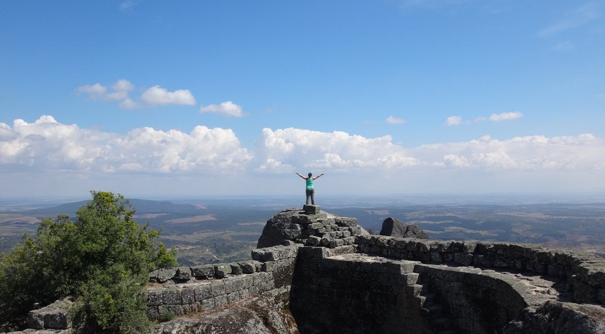 A man standing on top of a rock with his arms outstretched.
