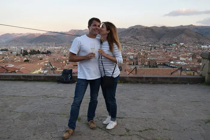 A couple kissing in front of a city with mountains in the background.