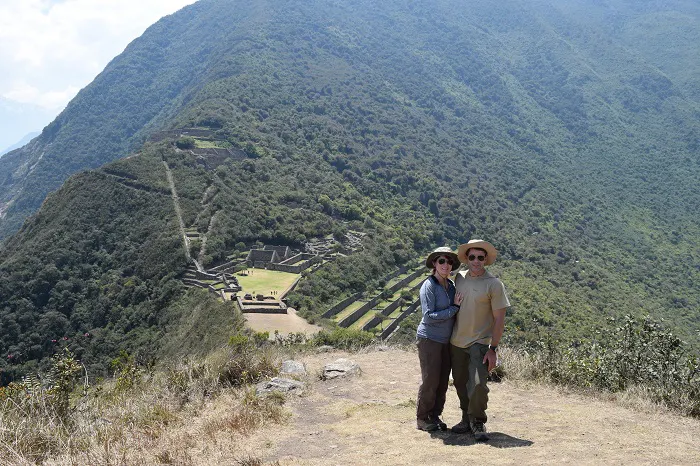 Two people standing on top of a mountain with a view of machu picchu.