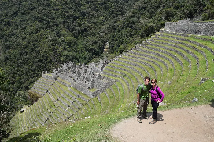 Two people standing on a path near the ruins of machu picchu.