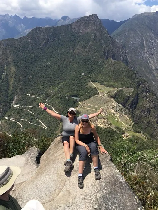 Two women posing on top of a mountain.
