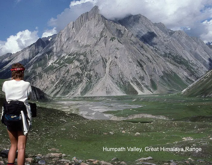 A woman is standing on a mountain overlooking a valley.