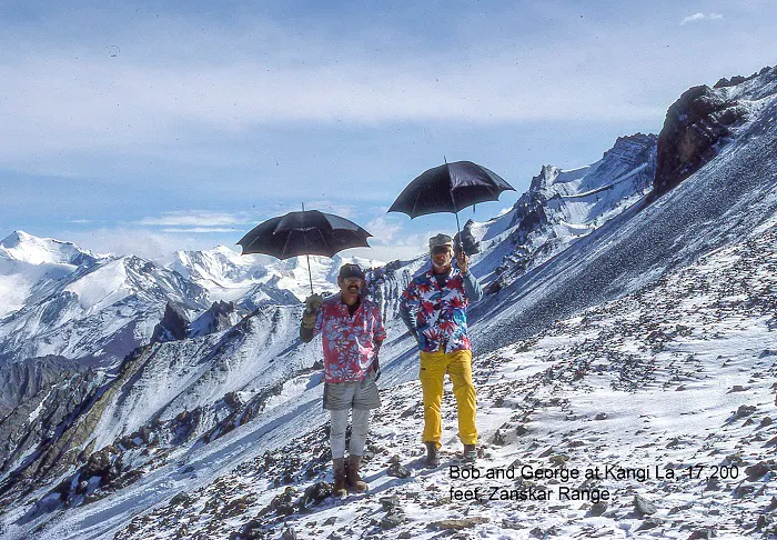Two people standing on top of a snow covered mountain.