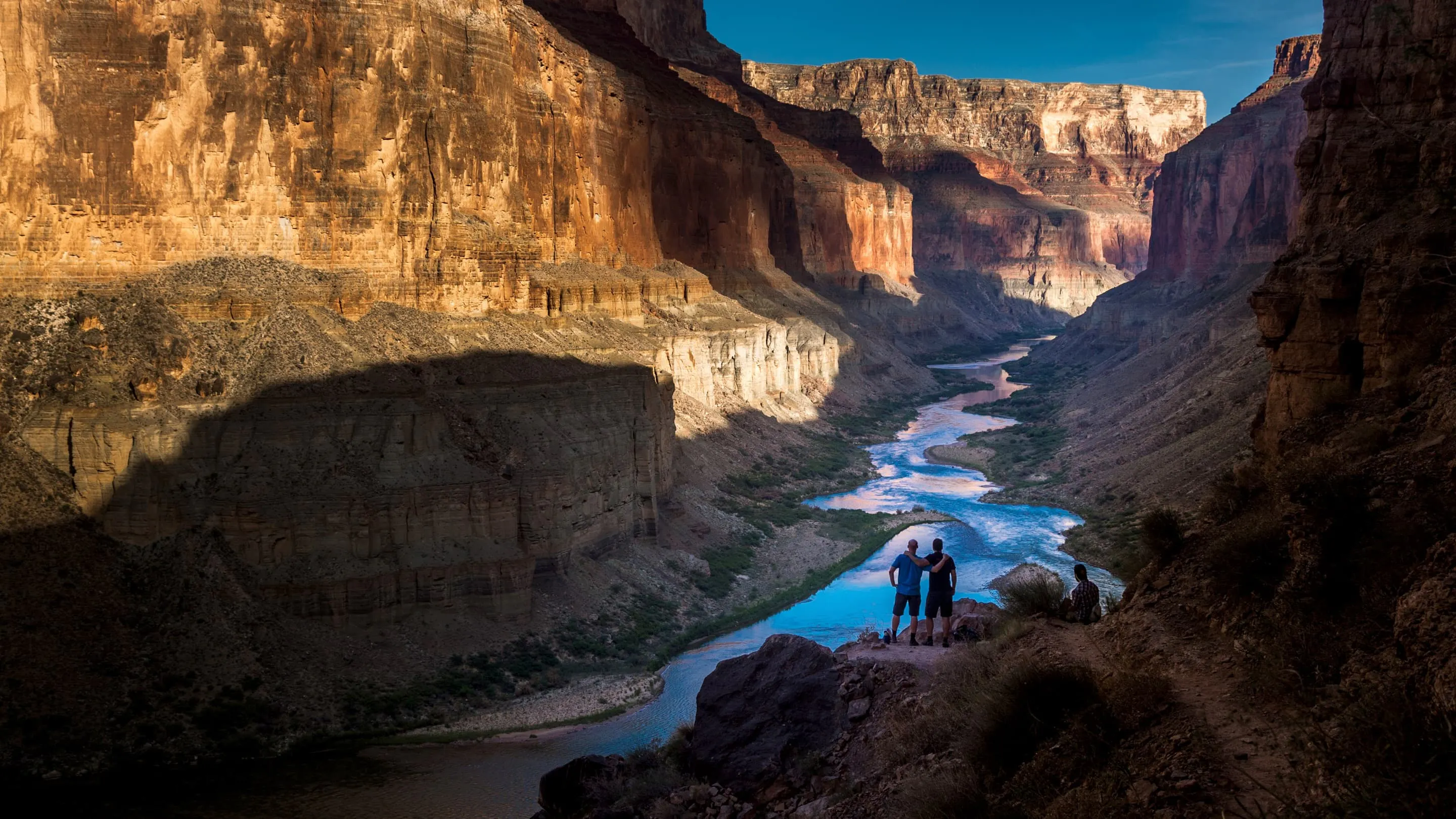 A couple standing on a cliff overlooking the grand canyon.
