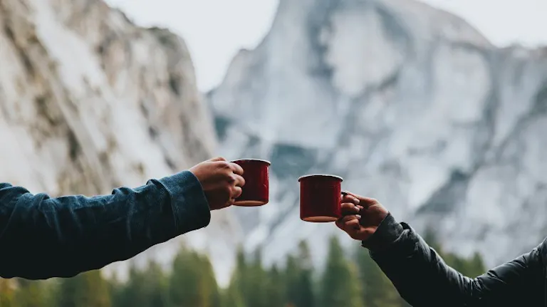 drinking coffee with a backdrop of a giant mountain 