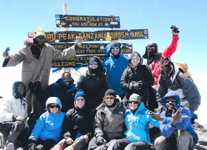 A group of people posing for a photo on top of a mountain.