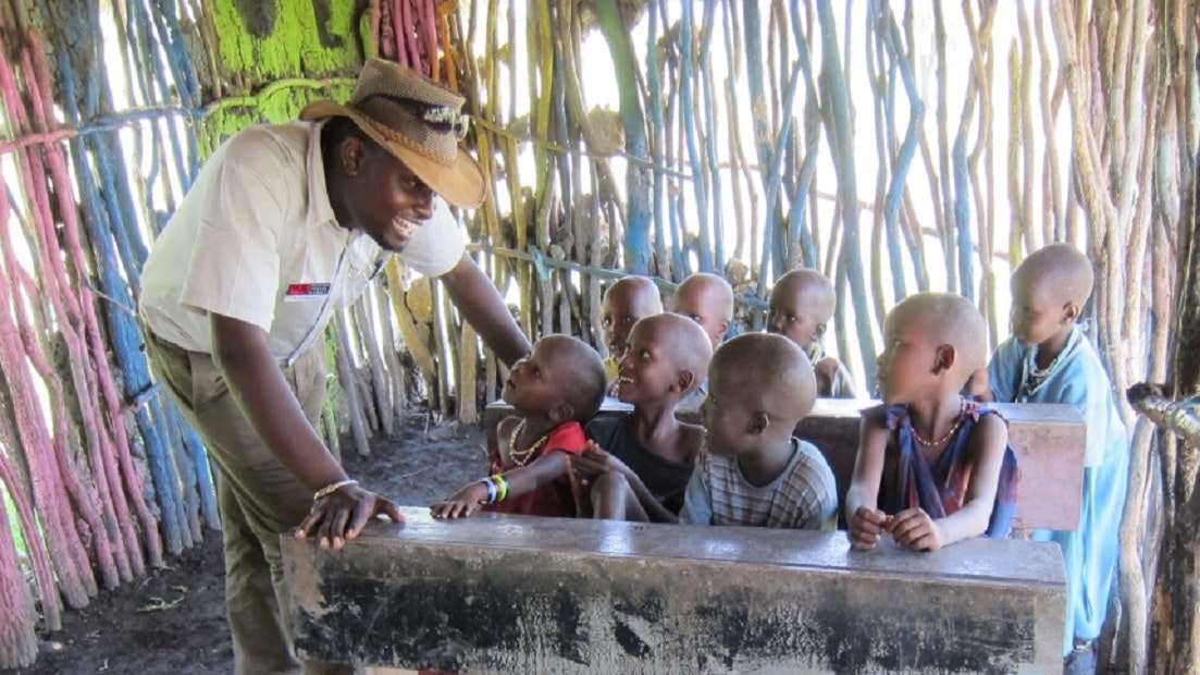 A man teaching a group of children in a hut.