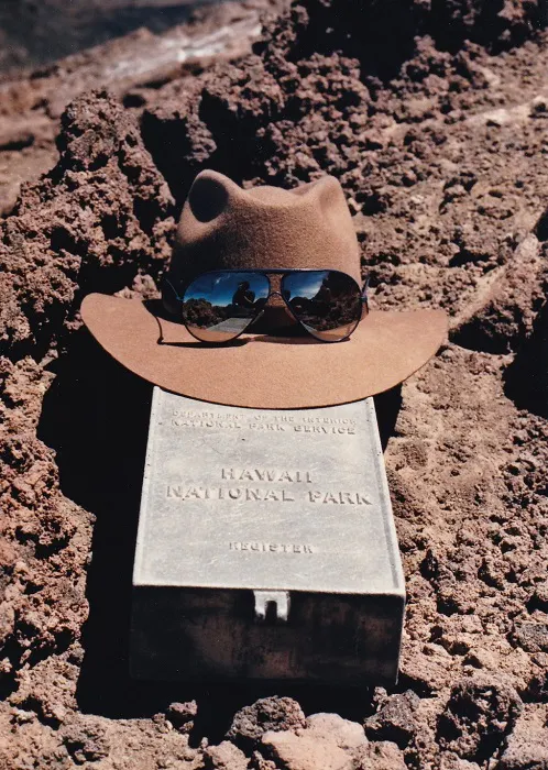 A hat and sunglasses sit on top of a rock in a national park.