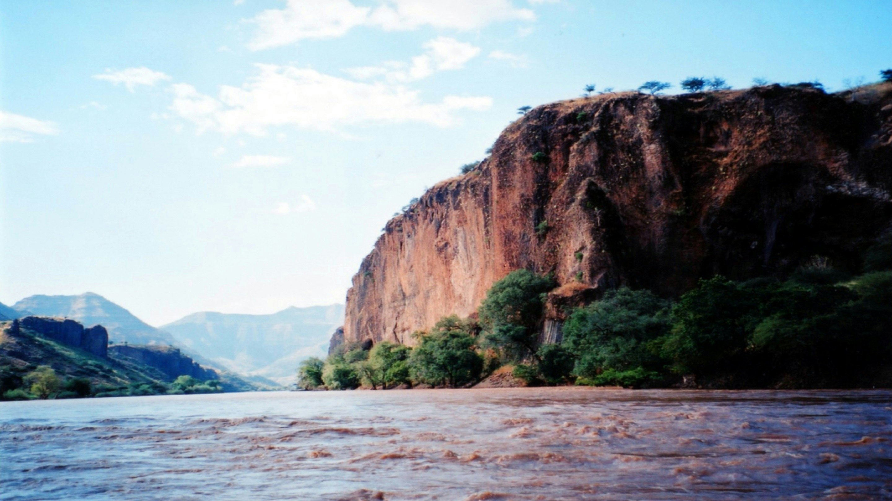 A river with a cliff in the background.