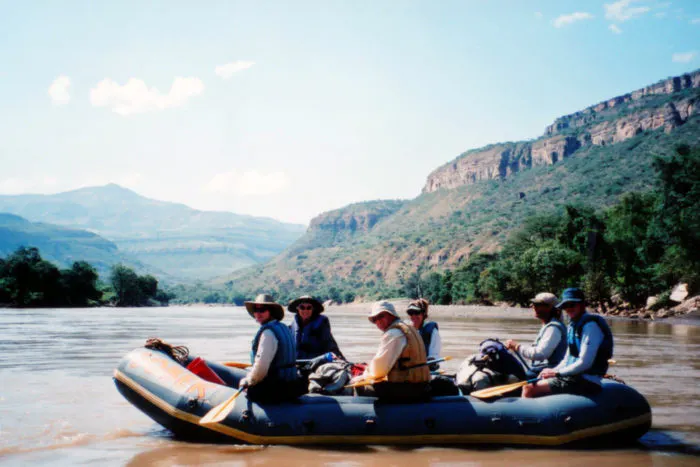 A group of people on a raft in a river.