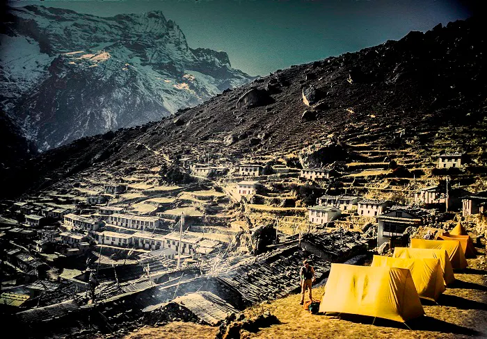 Yellow tents in a village with mountains in the background.