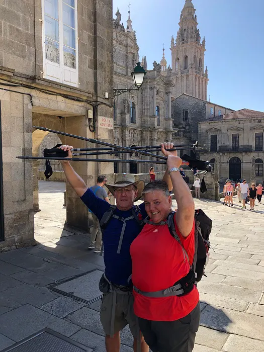 Two people standing in front of a building holding up a backpack.