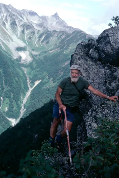 A man standing on a rocky ledge with a cane.