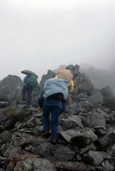 A group of people walking up a rocky mountain.