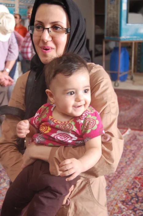 A woman wearing a hijab holding a baby.