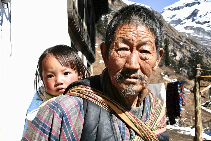 An old man carrying a child in the mountains.