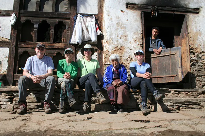 A group of people sitting on the steps of an old house.