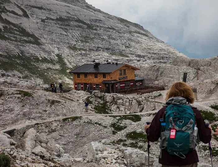 A woman is standing in front of a house on a mountain.