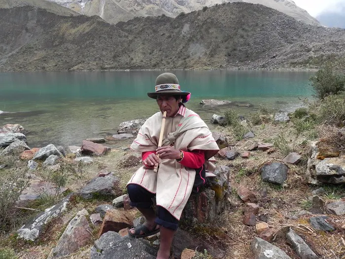A man sitting on rocks next to a lake.