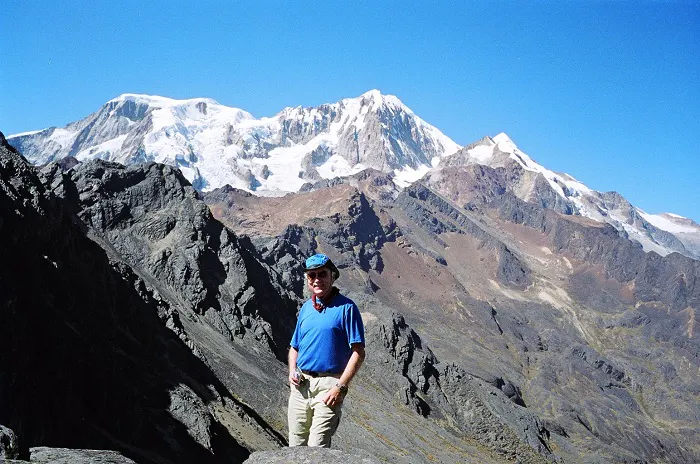 A man standing on top of a mountain with mountains in the background.