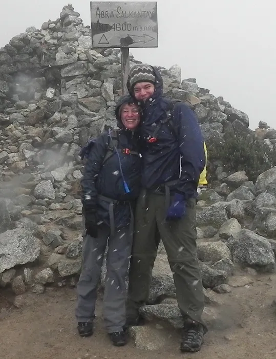 Two people standing on top of a mountain in the snow.