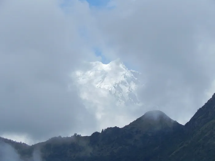 A mountain peak is seen through a cloudy sky.