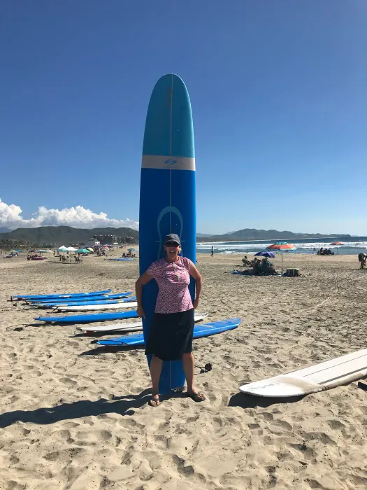 A woman standing next to a surfboard on the beach.