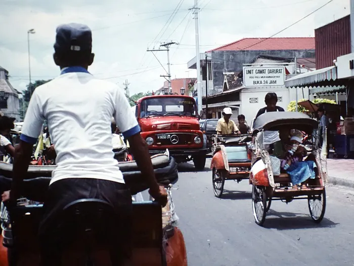 A group of people riding a rickshaw down a street.