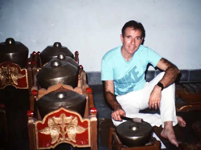 A man sitting in front of a group of wooden drums.