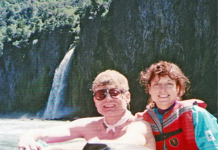 A man and woman on a raft near a waterfall.