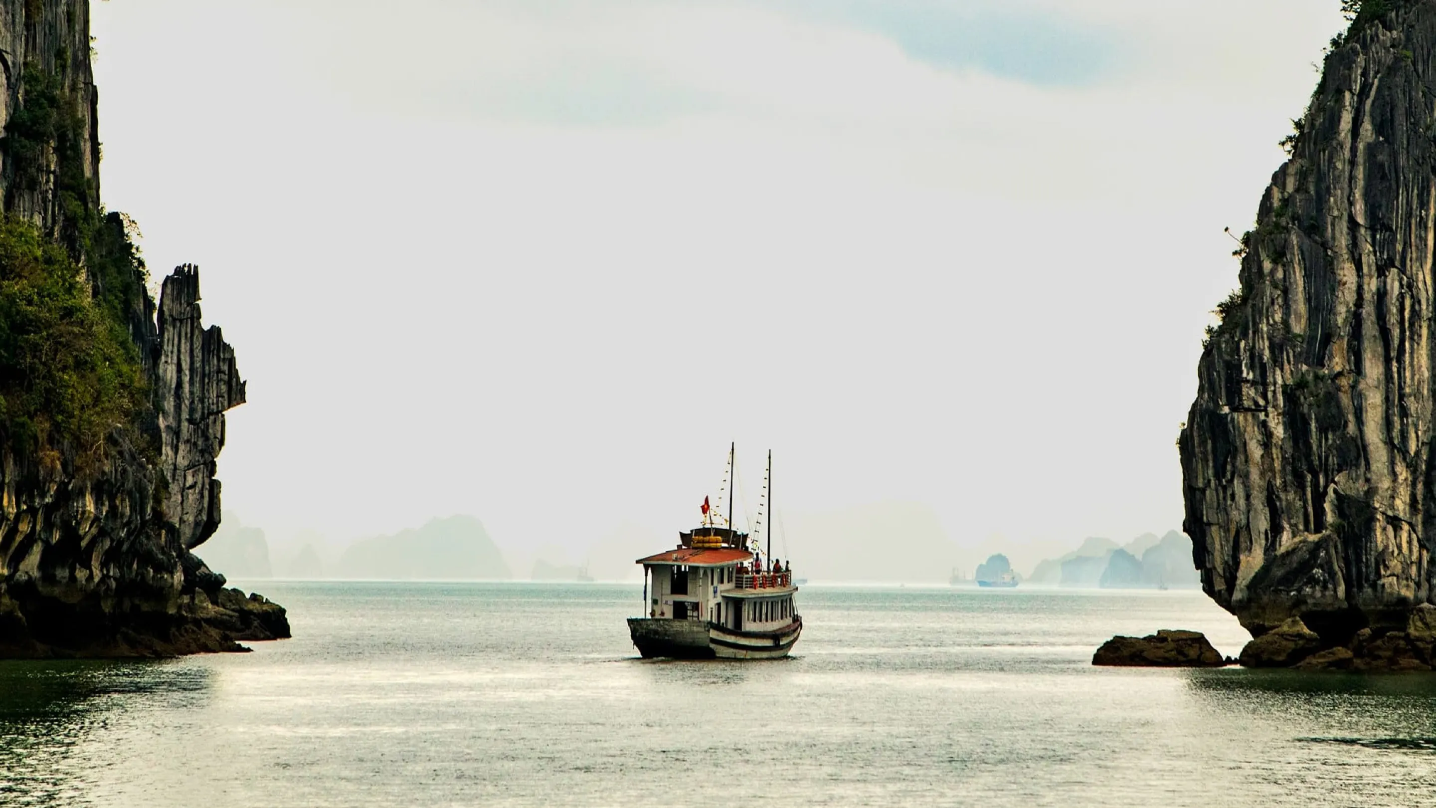 A boat is traveling through a body of water near cliffs.