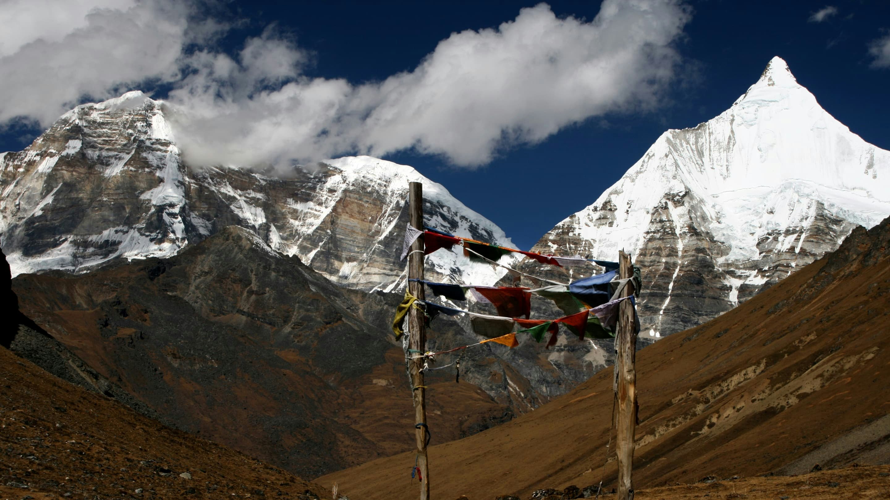 A group of prayer flags with mountains in the background.